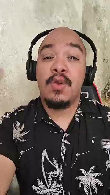 Adriano Ladislau em vídeo vertical usando fones de ouvido.